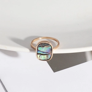 Macro detail of natural abalone shell inlay on minimalist golden rectangular ring