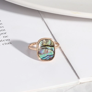 Close-up of rectangle abalone shell inlay on a rose gold ring with iridescent texture