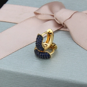 Detail of gold-plated hoop earrings with pave-set blue cubic zirconia on a gift box