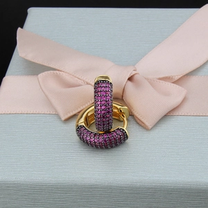 Detail of gold-plated hoop earrings with purple cubic zirconia on a gift box
