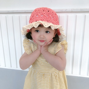 Close-up of pink-orange hand-woven straw hat featuring white lace trim and chic design