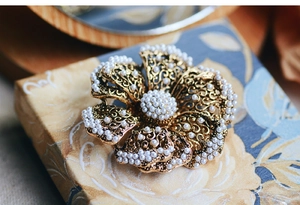 Close-up of a floral pearl brooch with golden metal petals and vintage flower design