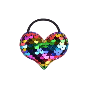 Macro shot of colorful glitter heart charm on elastic hair tie with vibrant rainbow sparkles