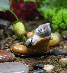 Macro detail of a cute grey cat sleeping in a yellow boot resin garden ornament