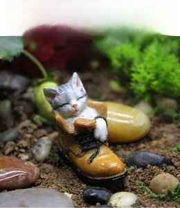 Detail of a miniature resin cat sleeping inside a brown shoe for garden decor