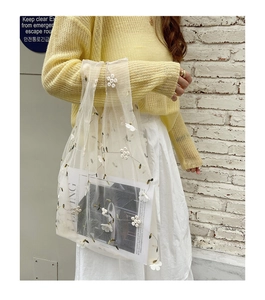 Detail of white embroidered flower mesh tote bag with sheer floral organza texture