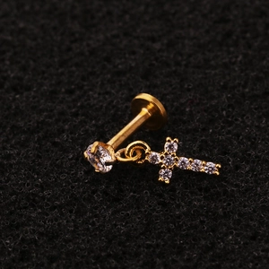 Golden flower labret stud with crystal cross pendant on a textured dark background