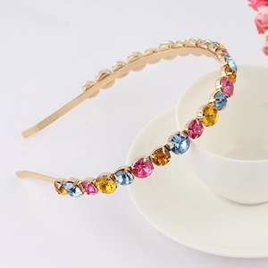 Detail of thin gold metal headband with colorful rhinestones on a ceramic cup