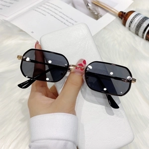 Chic black polygonal sunglasses with gold metal frame held against a lifestyle background