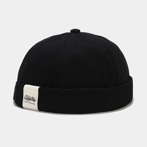 Detail of black cotton docker cap featuring a vintage white textile label on the side