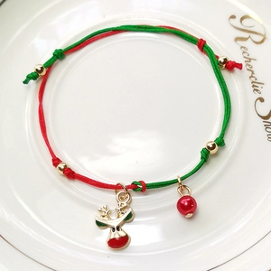 Macro view of Christmas woven bracelet with reindeer charm and red-green cord