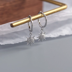 Macro shot of silver sunburst hoop earrings with sparkling cubic zirconia on a stand