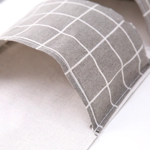 Gray checkered linen slippers with white stripes and detailed stitching in close-up