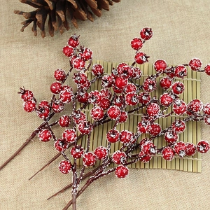 Close-up of frosted red Christmas berries on rustic bamboo mat with pine cones