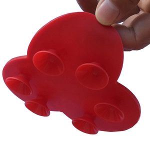Vista macro di un tappetino in silicone rosso con sei ventose tenuto in mano per scala