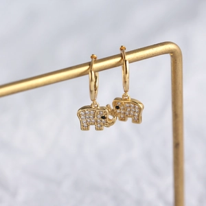 Vue détaillée de boucles d'oreilles éléphant dorées avec diamants sur un support