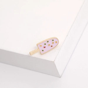 Macro detail of pink enamel ice cream pin with gold trim and colorful sprinkles