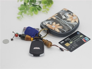 Detailed view of floral canvas coin purse with card and keys on a white table
