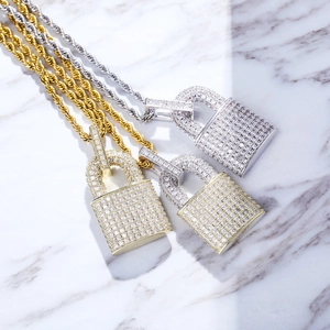 Detailed view of gold and silver lock pendants with zircon inlay on marble surface