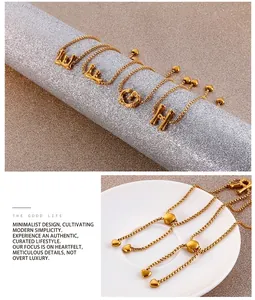 Dettaglio del bracciale regolabile con lettere dorate, catena a sfere e ciondolo a cuore