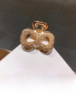 Close-up of golden bow hair claw clip with intricate embossed rose flower textures