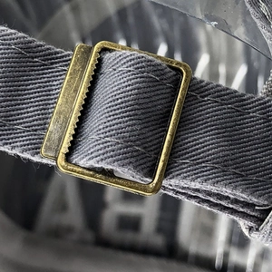 Gros plan sur la boucle en bronze vintage et la sangle réglable grise d'une casquette