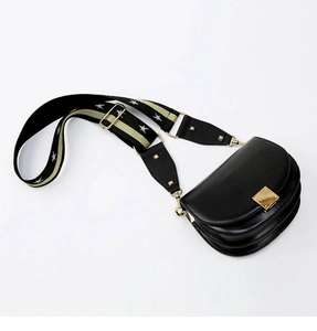Detail of adjustable star-patterned wide strap on black leather saddle bag with gold buckle