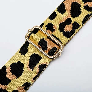 Close-up of leopard print bag strap with adjustable gold buckle and woven texture