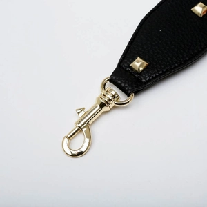 Close-up of black lychee leather bag strap with gold lobster clasp and square rivets