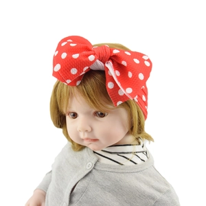 Detail view of baby headband with red and white polka dot pattern and large bow knot