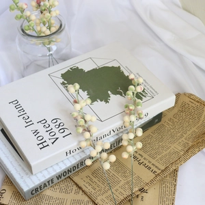 Detail of cream plush artificial berry stems on vintage books for holiday home decor