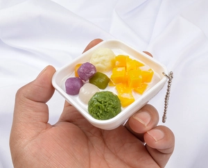 Close-up of mango taro ball dessert keychain held in hand showing small size