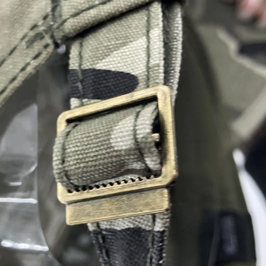 Detail of vintage bronze metal adjustment buckle and camouflage woven webbing strap