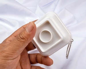 Close-up of a white square PVC charm base featuring a metal bead chain attachment