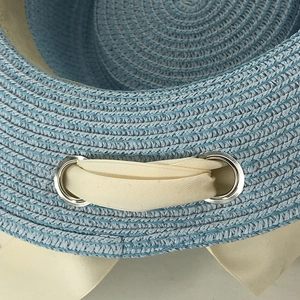 Detail view of woven sky blue sun hat with cream ribbon and silver metal eyelet detail