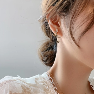 Detailed close-up of a butterfly stud earring with sparkling crystals on a female ear