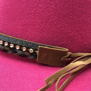 Detailed close-up of dark pink wool fedora hat with rhinestone and leather band