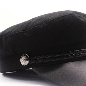 Detail of wool newsboy cap with braided rope and embossed silver metal button accent