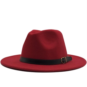 Détail du chapeau fedora rouge en laine avec bande en cuir noir et boucle dorée