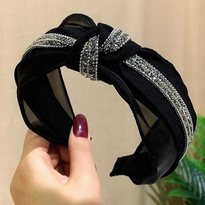 Close-up of black mesh polka dot headband with rhinestones and center knot detail