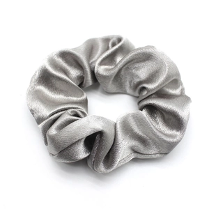 Macro shot of grey satin scrunchie showing glossy texture and elegant fabric folds