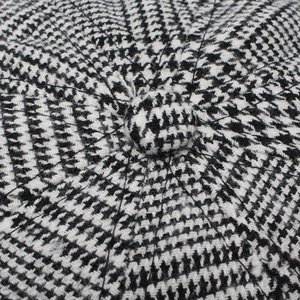 Close-up of houndstooth newsboy cap top detail with black and white tweed pattern