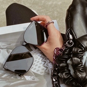 Close-up of black oversized square sunglasses with silver metal bar details on arms