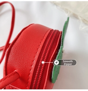 Close-up of the smooth red zipper and textured leather material on strawberry bag