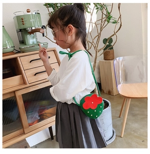 Toddler strawberry-shaped crossbody bag shown in a cozy home setting lifestyle view
