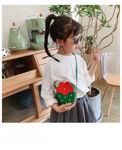 Detail showing toddler wearing the strawberry style rivet handbag with green strap