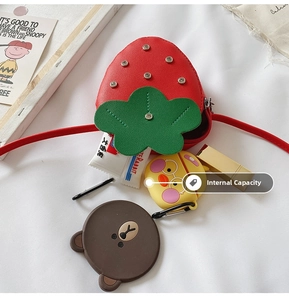 Detail of red strawberry crossbody bag showing storage capacity with cute accessories