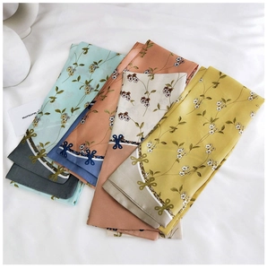 Flat lay of double-sided floral silk scarves in light blue, pink, beige, and yellow colors