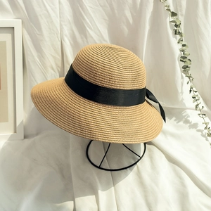 Detail of woven straw sun hat with black ribbon on a stand against a vintage background