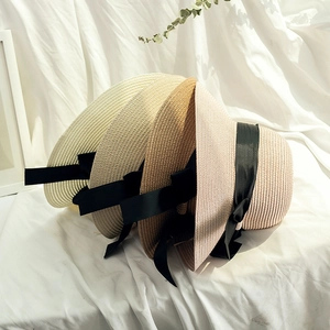 Detail of woven straw sun hats in various colors with elegant black ribbon bow accents